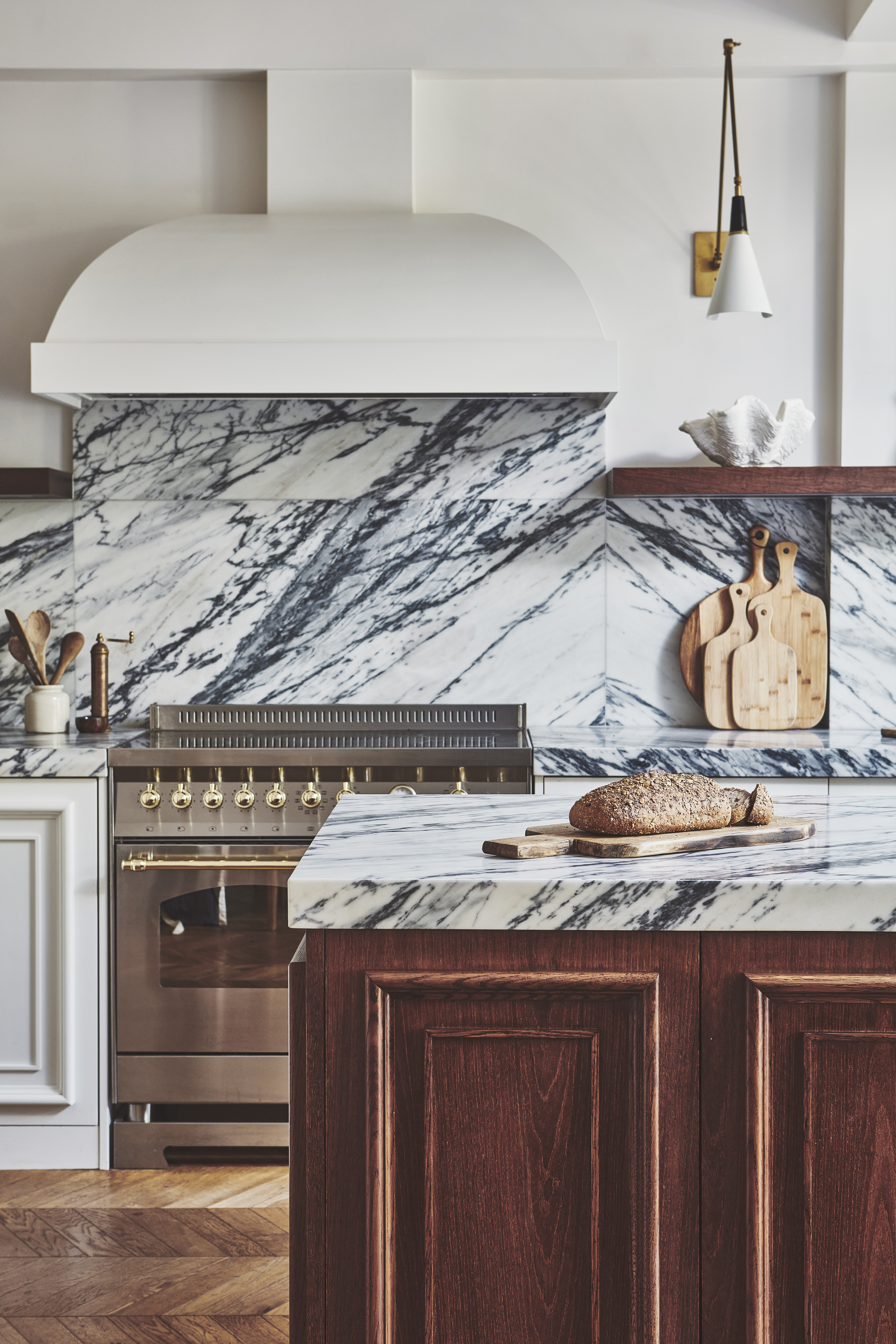 beautiful traditional kitchen with dark wooden cabinets, marble counters, and a large, silver range cooker
