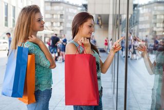 Two teen girls go shopping at upscale stores.