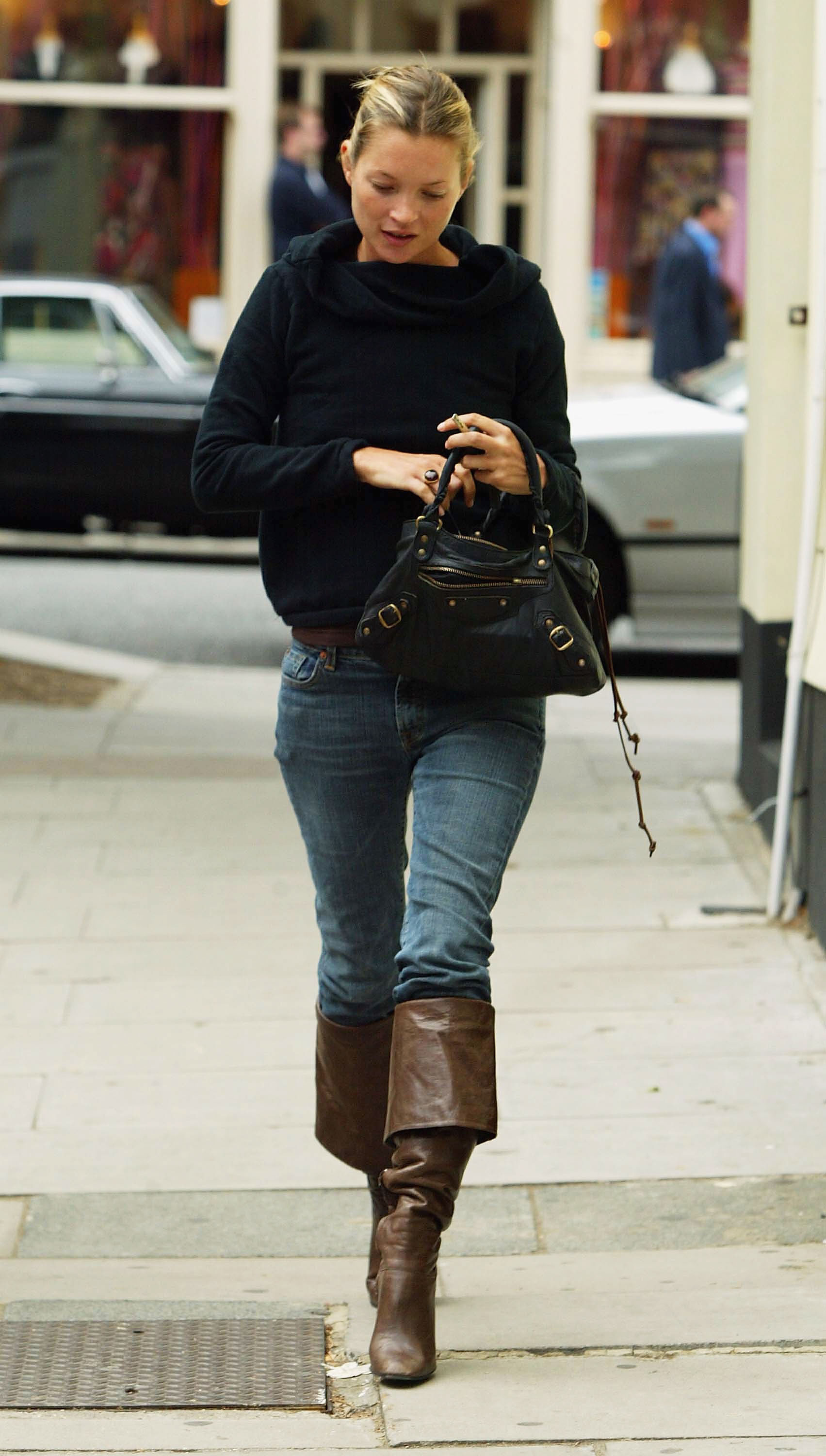 Kate Moss wears the tucked knee high boot trend, she wears pirate boots with blue skinny jeans and a knitted tee in 2003. This image was taken from Getty.