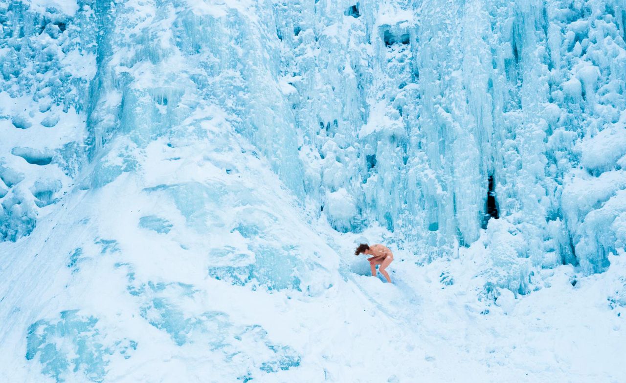 Naked woman hunched over in a frozen landscape