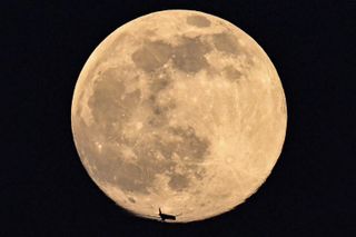 A plane is silhouetted against full moon also known as Worm moon in Moscow on March 17, 2022.