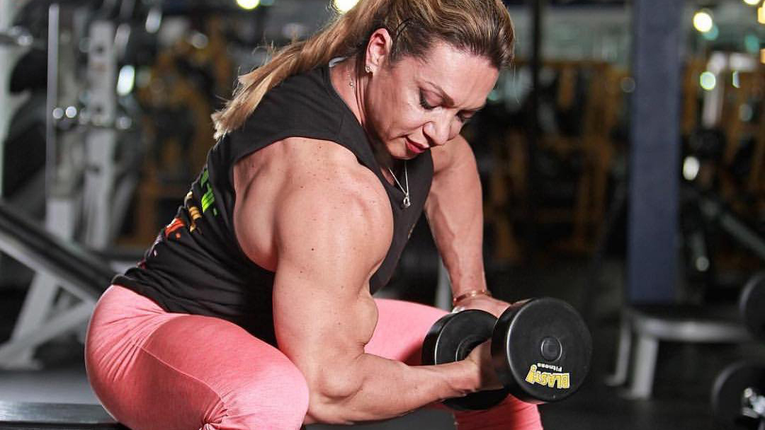 Fitness woman showing fit strong arms triceps and shoulder. Female  bodybuilder athlete flexing muscles after outdoor workout at the beach.  Stock Photo