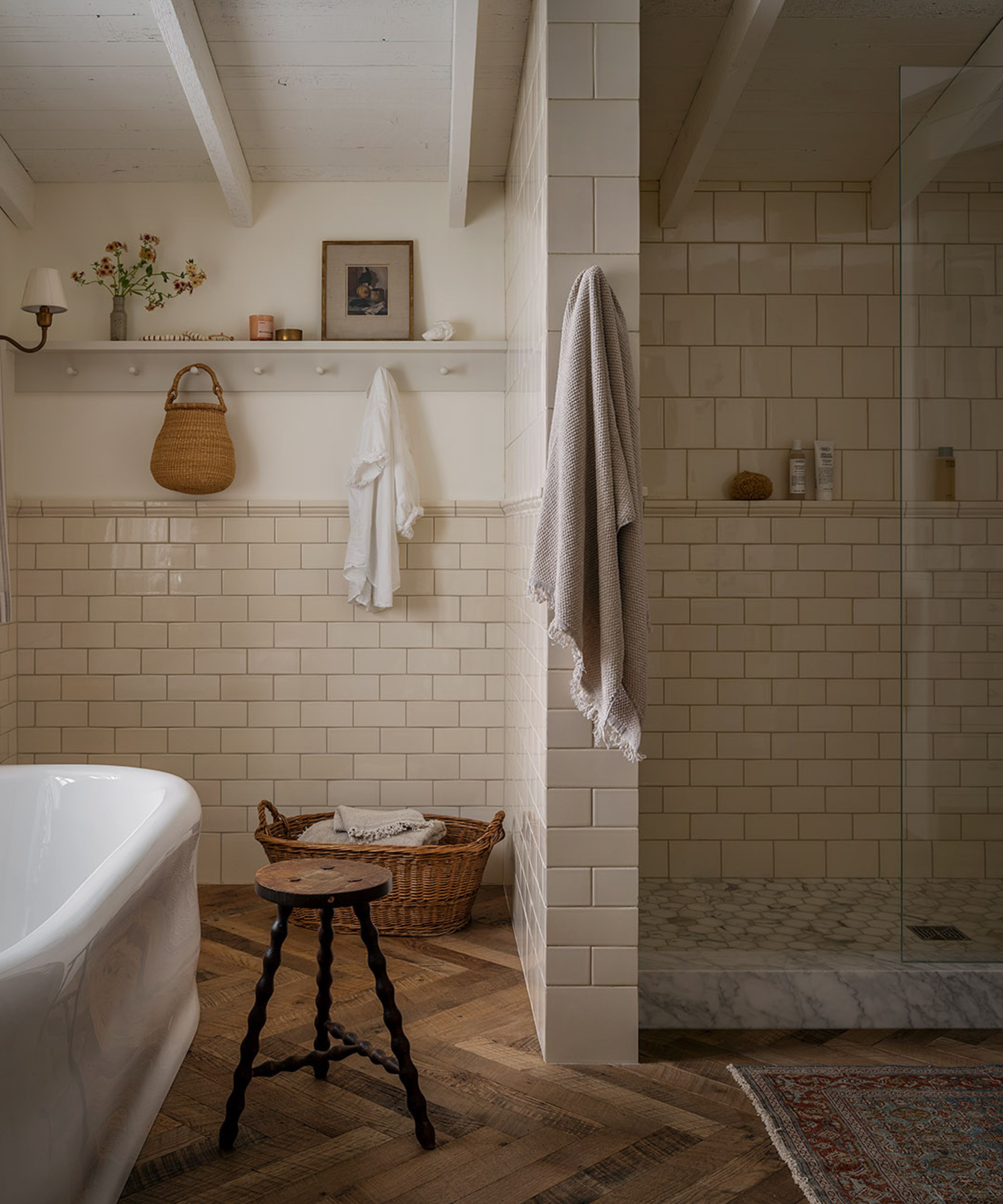 a warm white bathroom with cream subway tiles and a tiled walk in shower