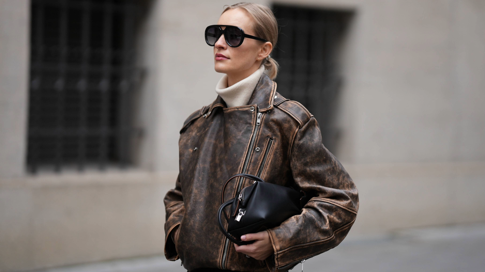 MUNICH, GERMANY - NOVEMBER 7:Marlies Pia Pfeifenhofer is seen wearing a distressed brown leather biker jacket with a stand-up collar and asymmetrical zip-up front by H&amp;M Studio; a beige cashmere turtleneck sweater by Allude; a structured black leather baguette bag with long handles and brown accent details by Max Mara; oversized aviator sunglasses with a double-bridge frame by Kaleos; her blonde hair is styled in a sleek low bun on November 7, 2025 in Munich, Germany. (Photo by Moritz Scholz/Getty Images)