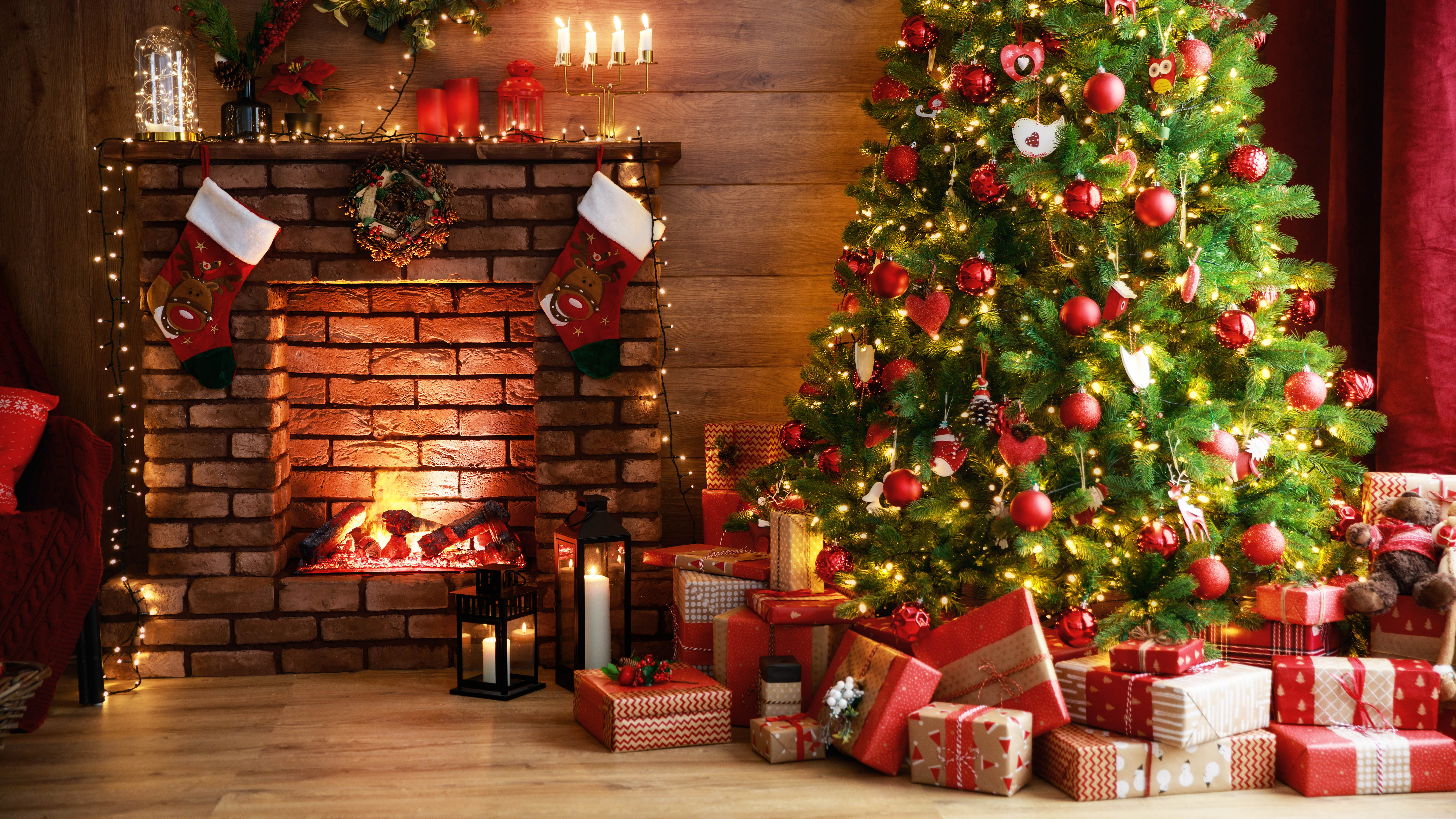 Украшенная рождественская елка с подарками рядом с камином.