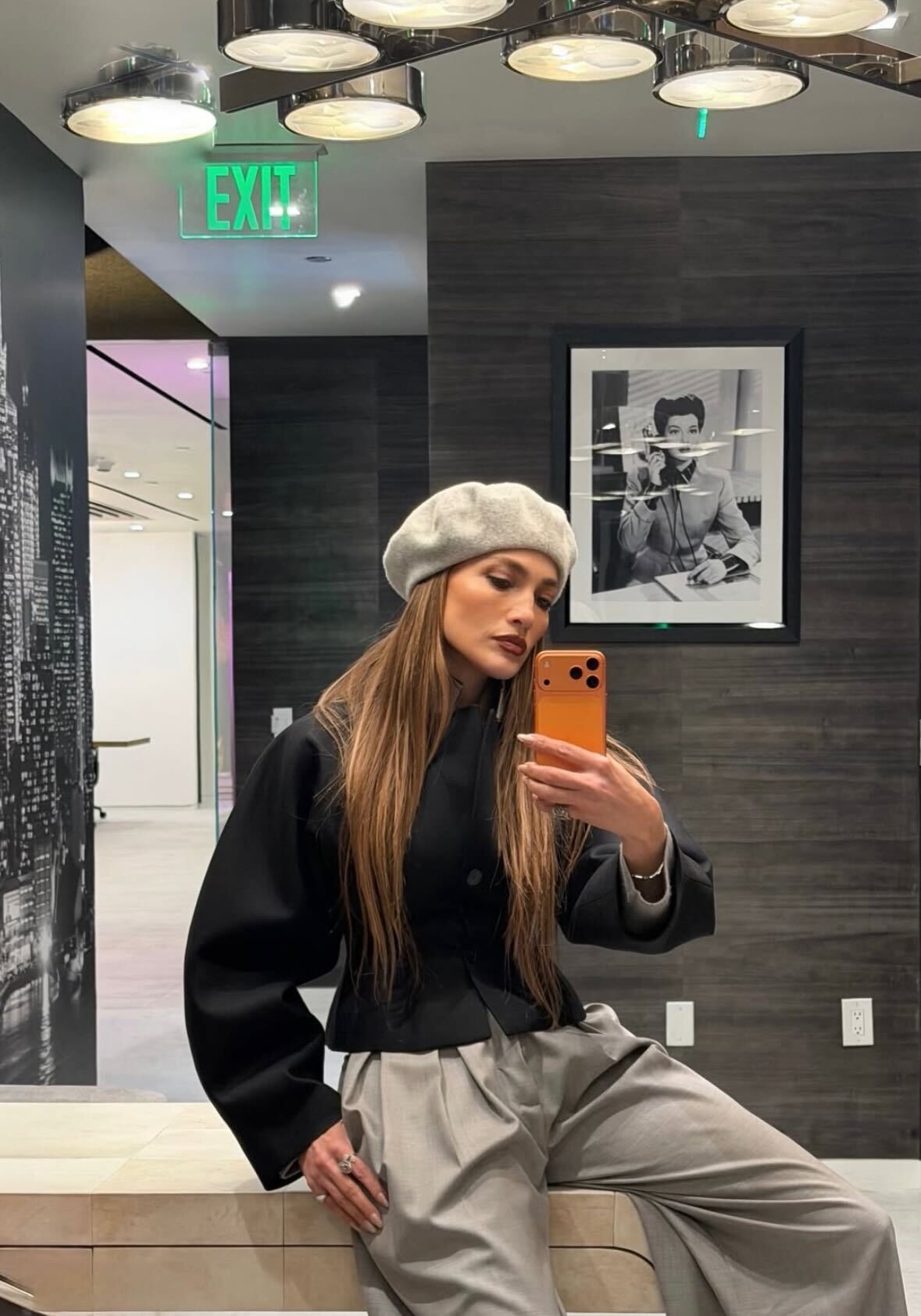 J.lo wears a gray beret, black top, and light gray trousers.
