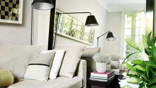 small living room with large mirror at the end of the sofa reflecting views of the garden to show how to make a small living room look bigger