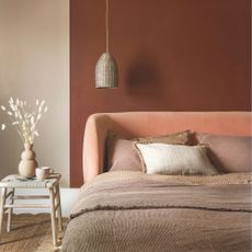 A curved headboard in a light velour fabric, against a deep red wall