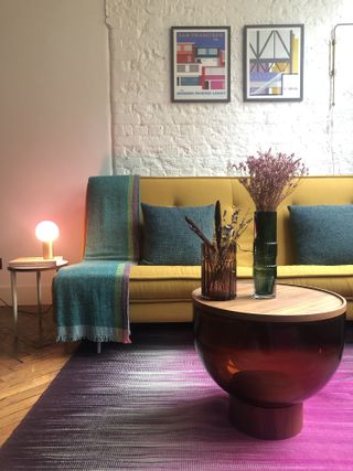 Living room with mustard sofa, purple rug and layered soft lighting