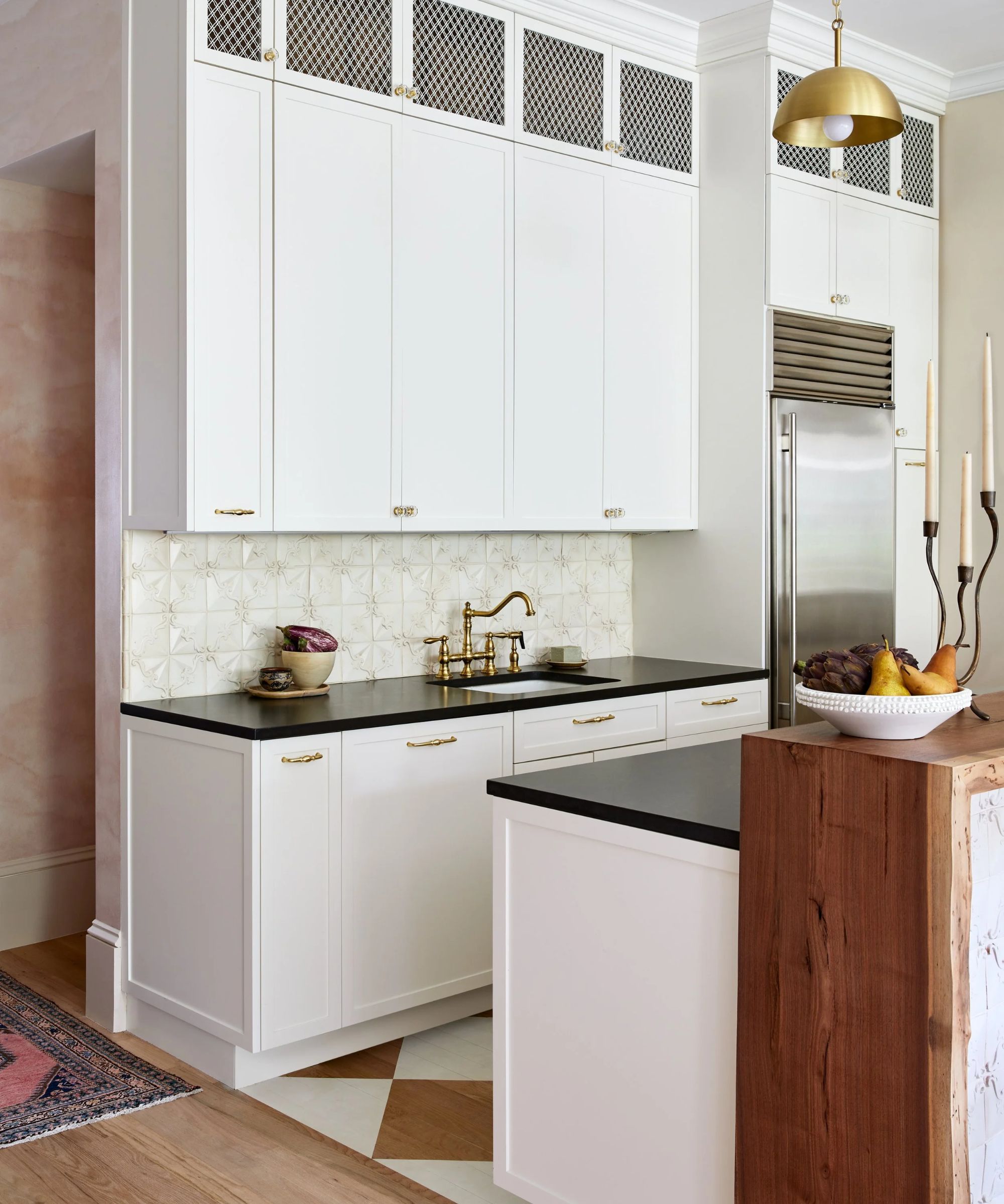A small white kitchen with black countertops and a painted wooden checkerboard floor