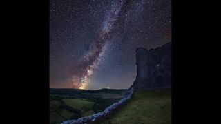 Vibrant Milky Way over landscape of medieval castle ruins at Brecon Beacons National Park, in Wales.