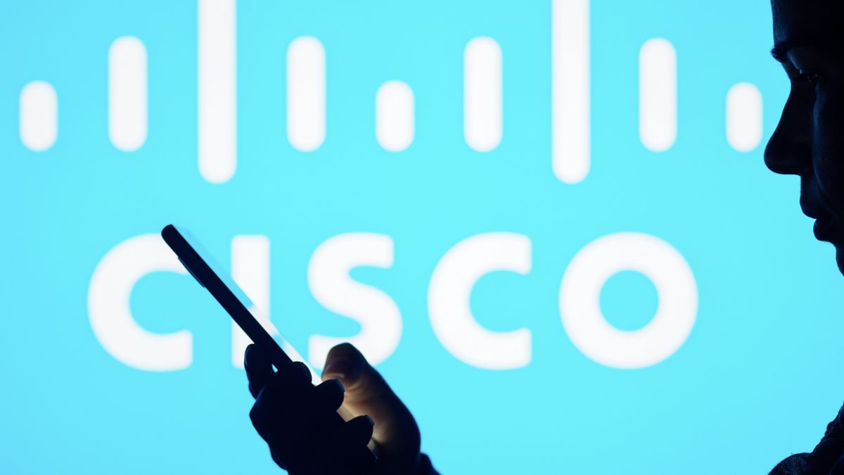 Somebody holding a smartphone in front of a Cisco logo