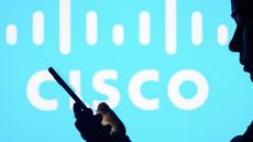 Somebody holding a smartphone in front of a Cisco logo