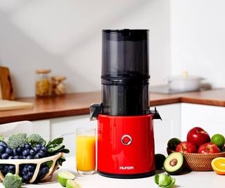 A Hurom Slow Juicer on a kitchen counter with fruit and veg.