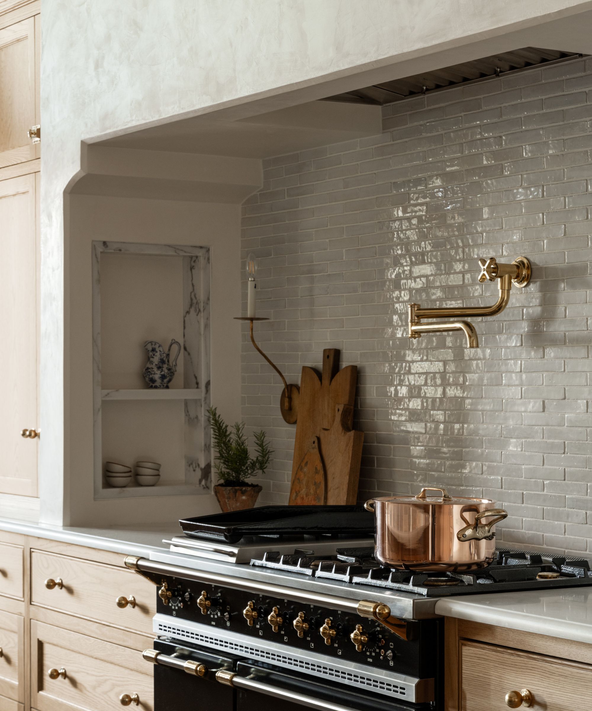 A range area with niches on each side for storage and a white zellige tiled backsplash