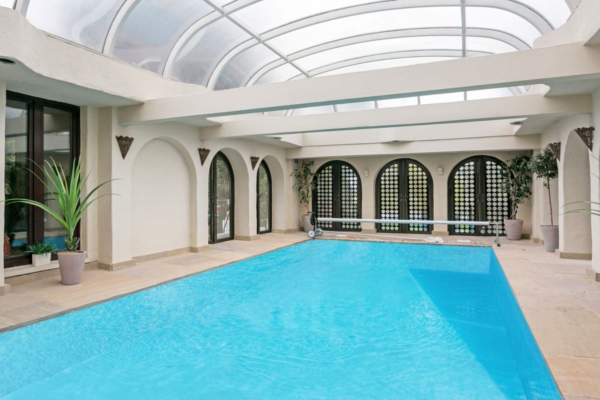 The house has a pool at its centre and has potted plants around.