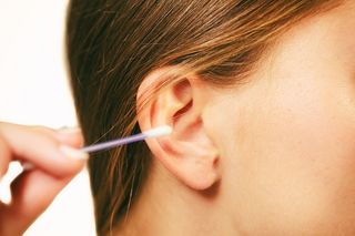 A woman putting a cotton swab in her ear.