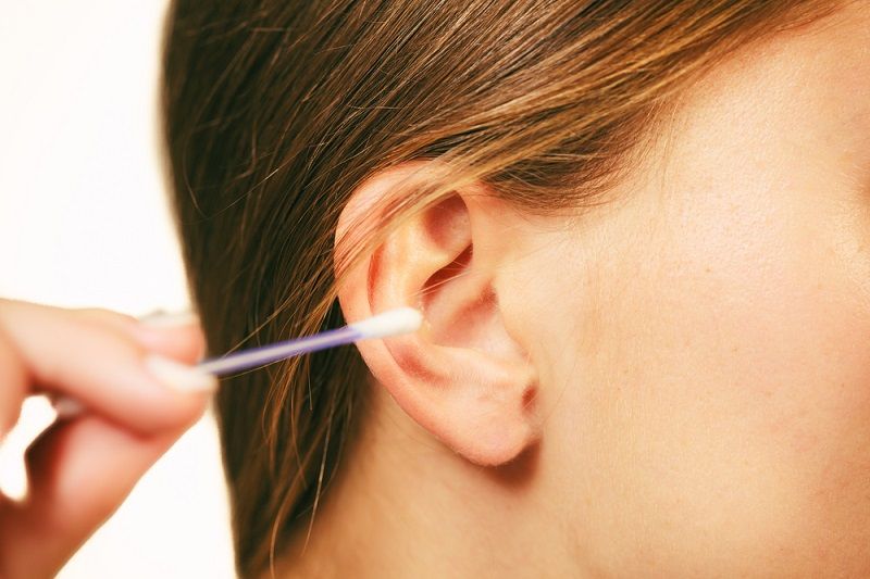 A woman putting a cotton swab in her ear.