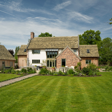 A large green lawn whith lawn stripes in front of a large rustic cottage.