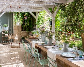 outdoor dining area under a wooden pergola of a country home