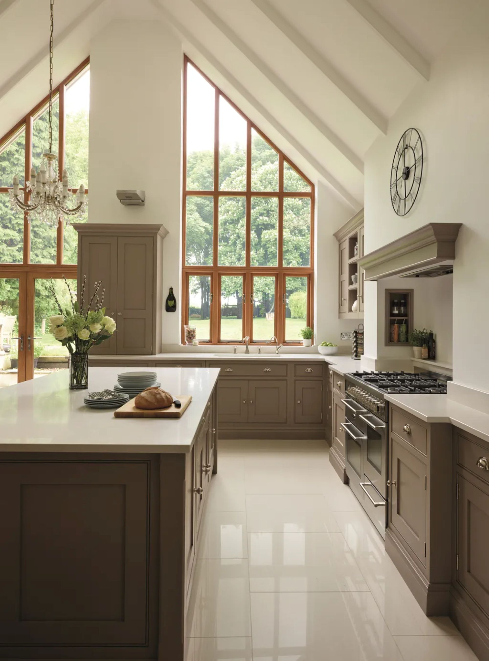 a large kitchen with taupe cabinets, white countertops, and large trapezoid windows