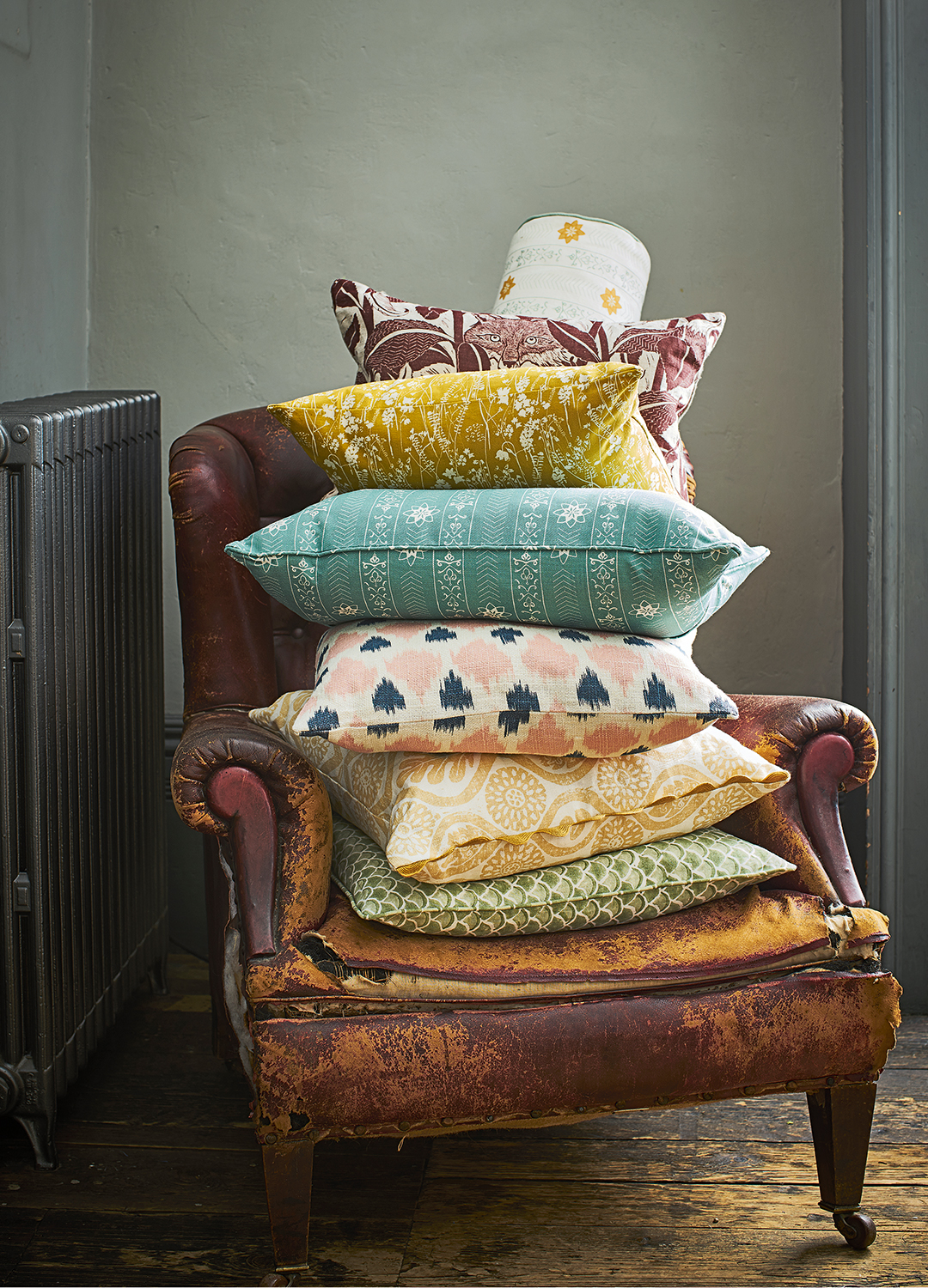 Distressed leather armchair with a stack of cushions pushed up against a radiator