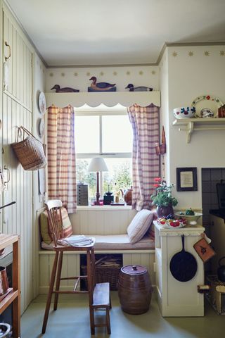window seat infront of window with cushions and curtains