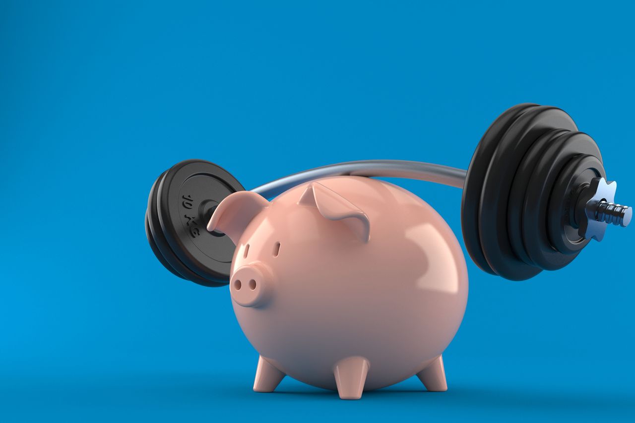 Piggy bank lifting barbell weights on blue background, symbolising financial resilience