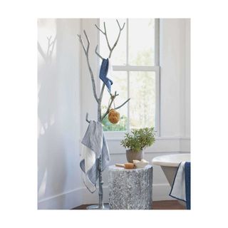 Silver towel tree with relaxed, hanging linens and natural sponge.