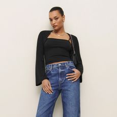 model wears black shrug set and jeans 