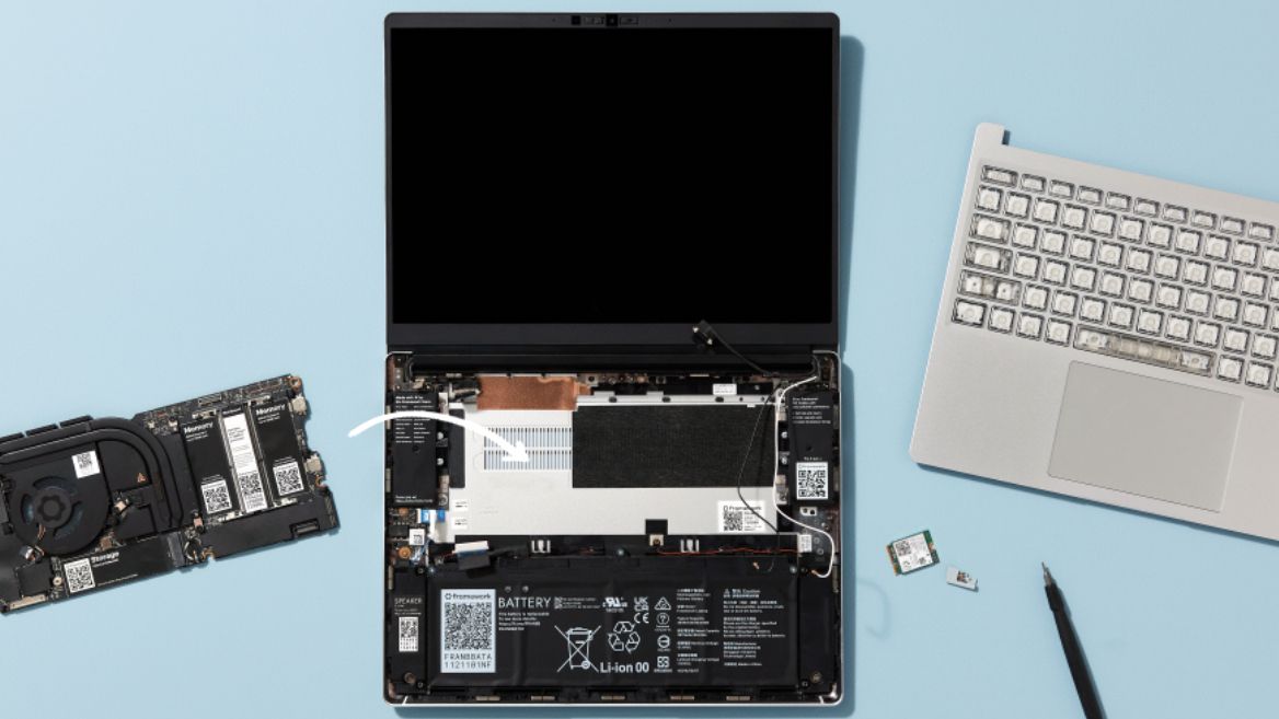 Framework Laptop open on blue background showing parts being removed