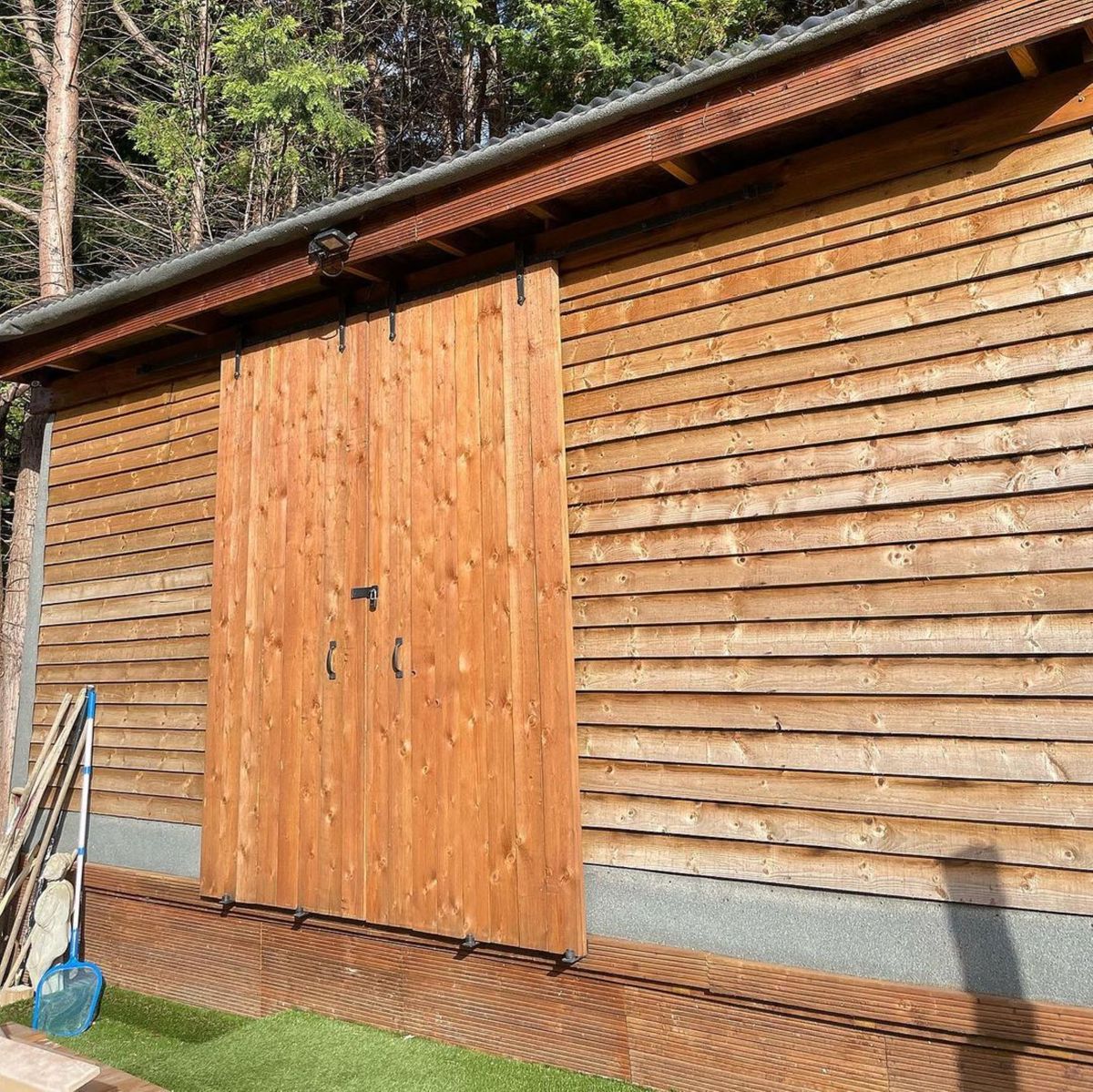 The previous garden shed shows a simple wood panelled shed with a flat roof and double wide wooden door