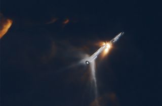 A giant rocket separating during stage separation, with fiery plumes in all directions.