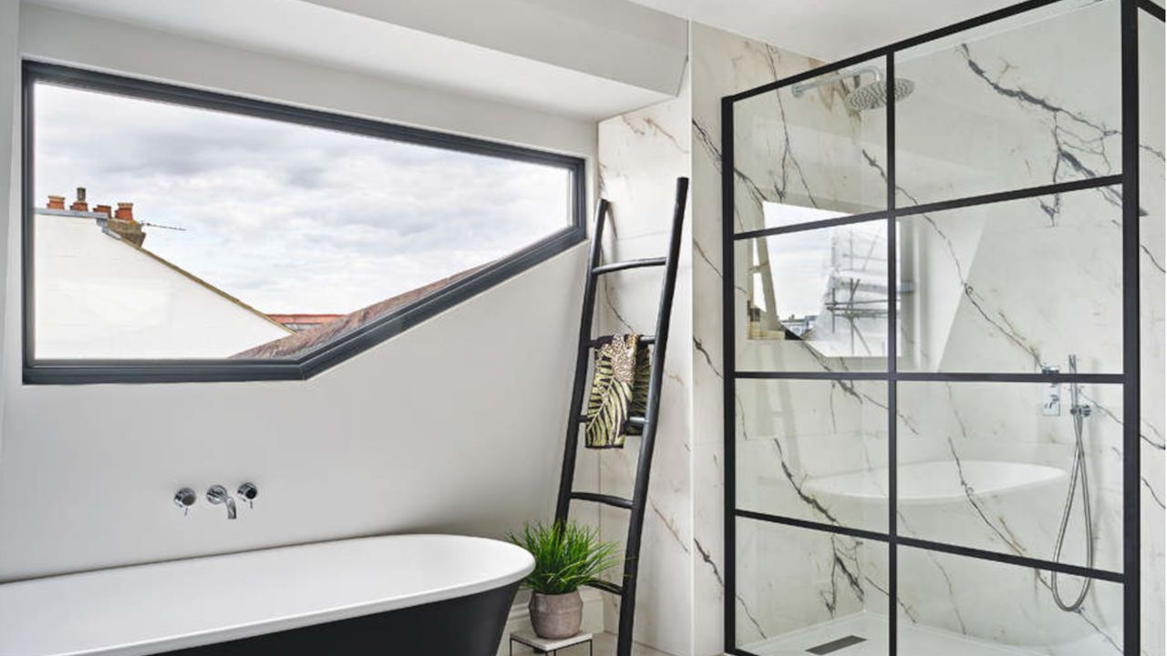 bathroom with walk-in shower with shower screen, freestanding bath, black towel rack and large wall window 