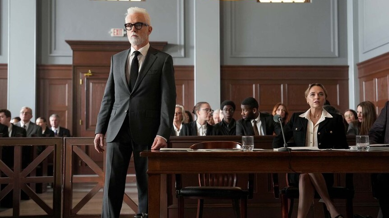 John Slattery as Leo F. Drummond (standing) with Madison Iseman as Sarah Plankmore (seated) in The Rainmaker 