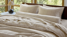 Beige Parachute yarn-dyed striped bedding photographed on a large bed surrrounded by large windows