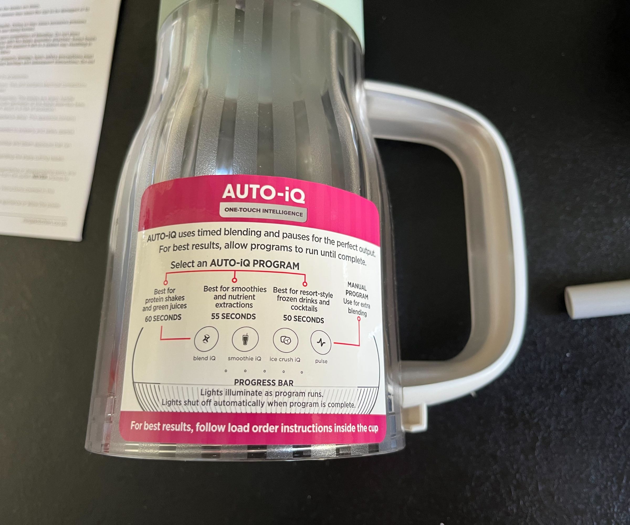 A close up of the Auto-IQ instruction sticker on the side of a clear plastic tumbler on a black counter