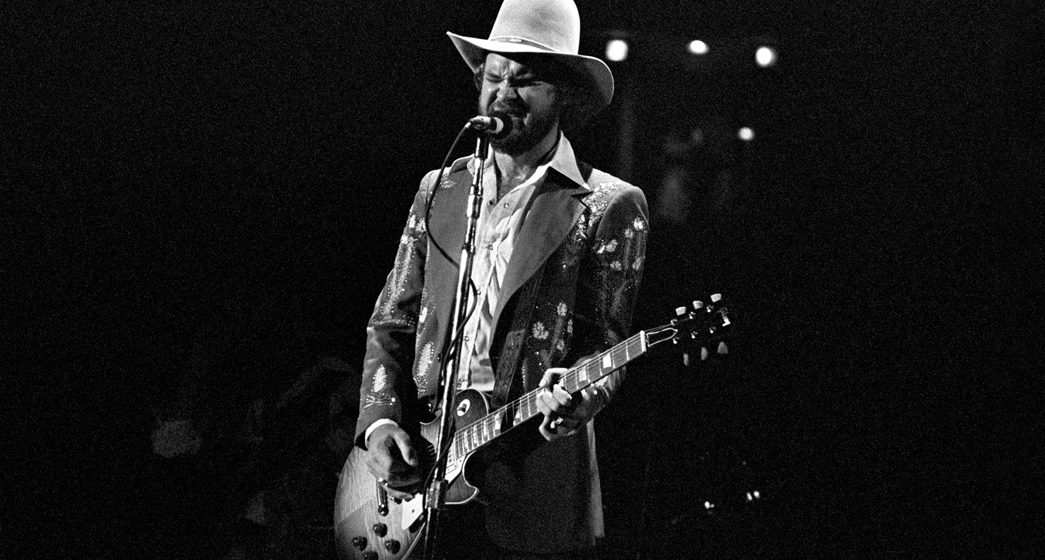 Billy Gibbons onstage with Pearly Gates, wearing a large cowboy hat with his beard yet to grow to regulation ZZ Top length.