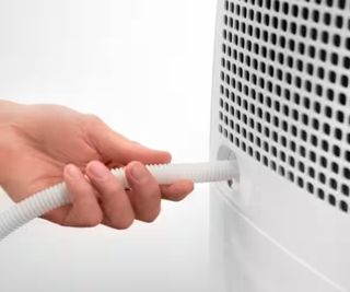 hand inserting white slim pipe into rear of dehumidifier