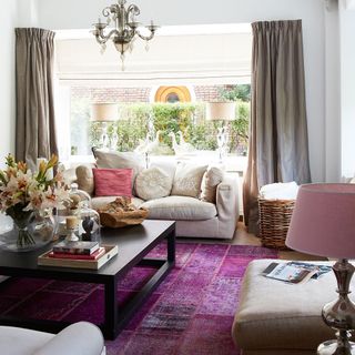 A neutral living room with a dark purple rug and black coffee table