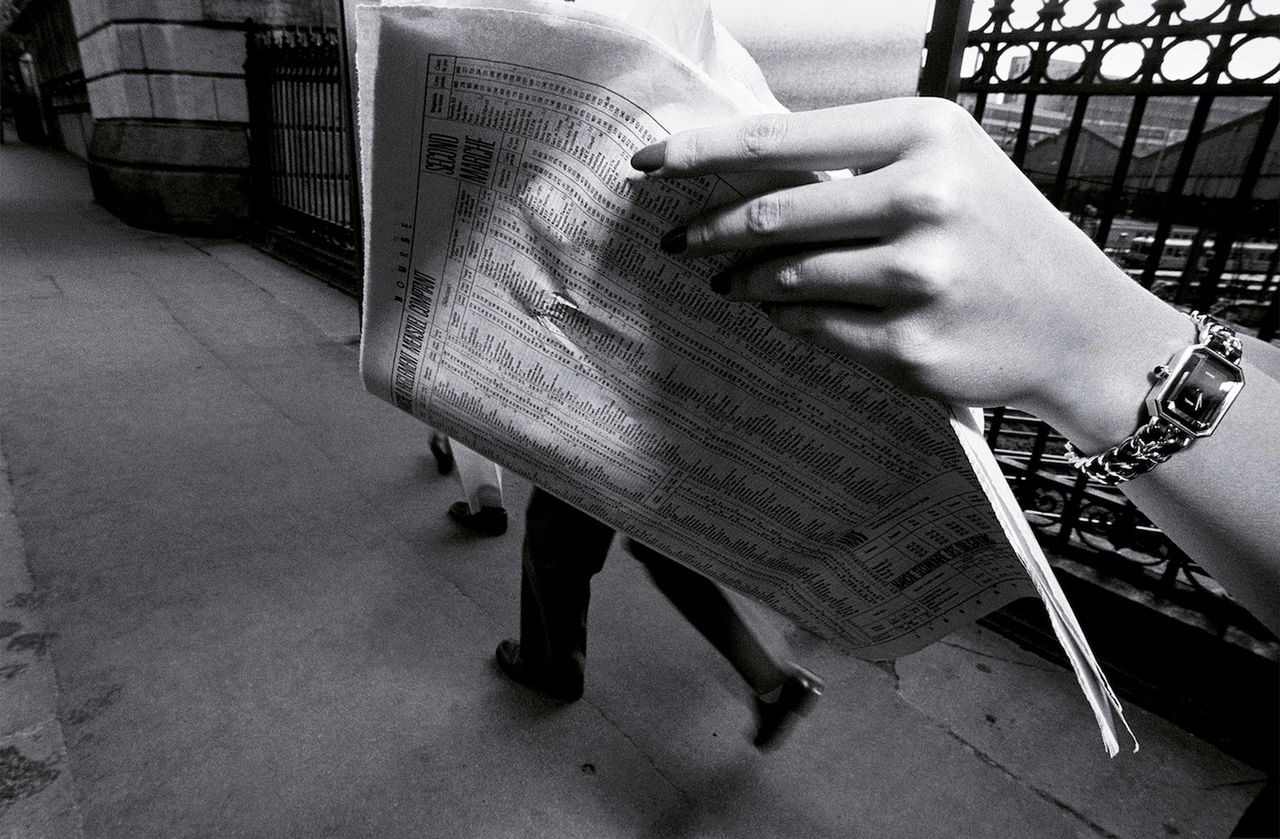 Womans arm with Chanel watch holding newspaper