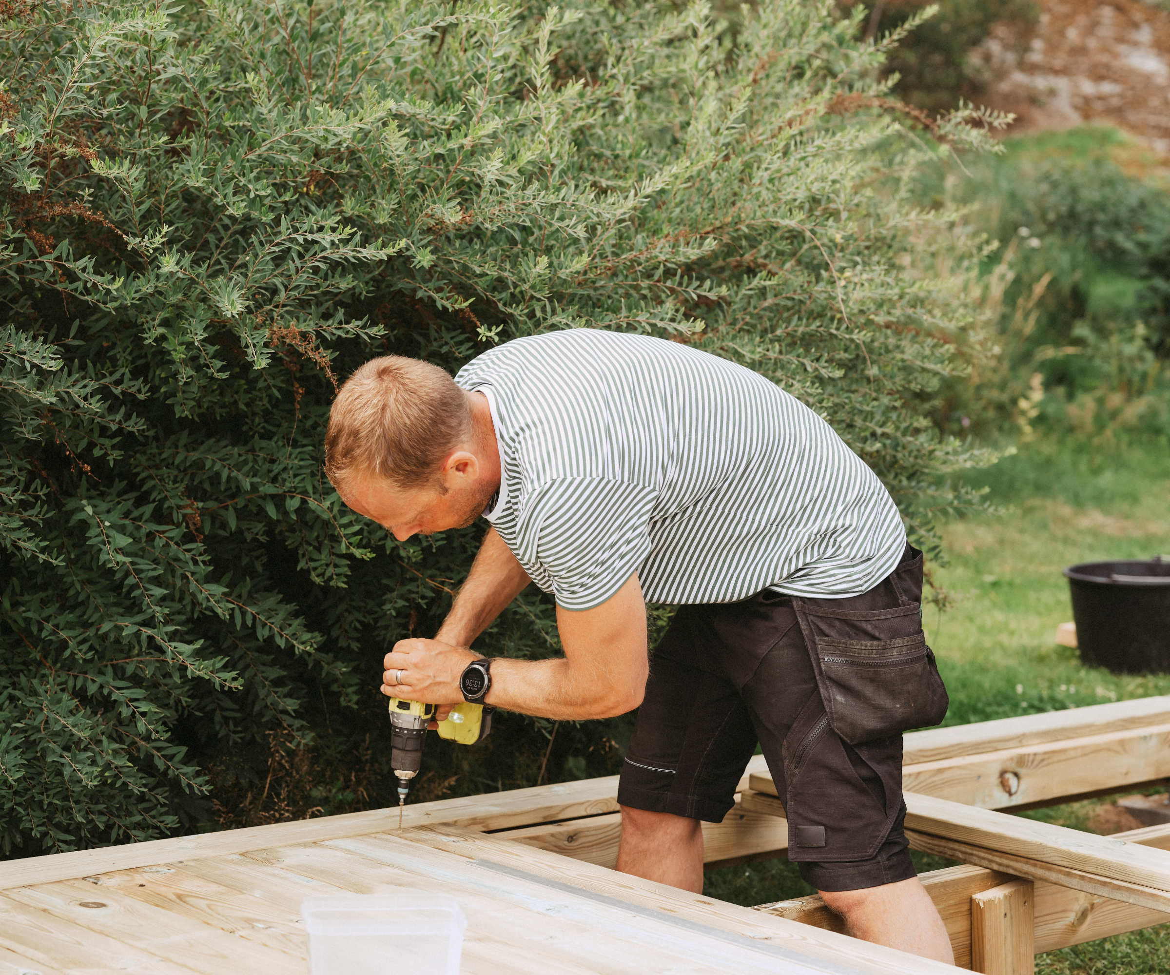 Man drilling decking in garden