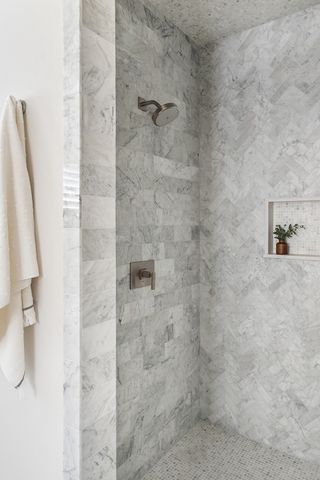 walk in shower with marble subway tiles lai d in different patterns