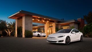 Two while Tesla's parked outside a grand, modern house