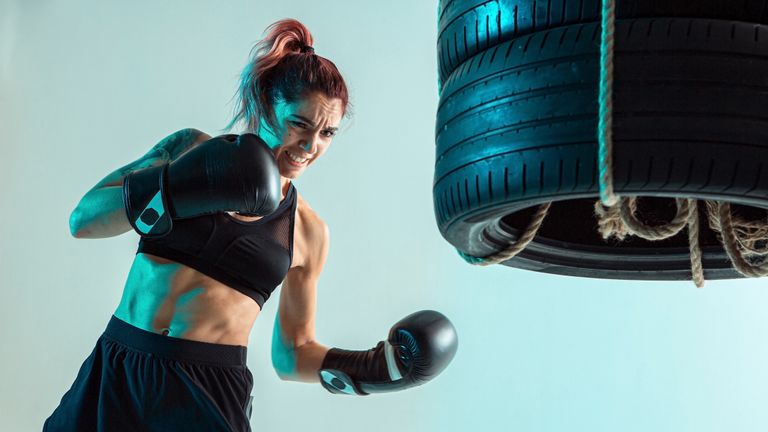 person using boxing gloves to punch some suspended tyres in a photo studio