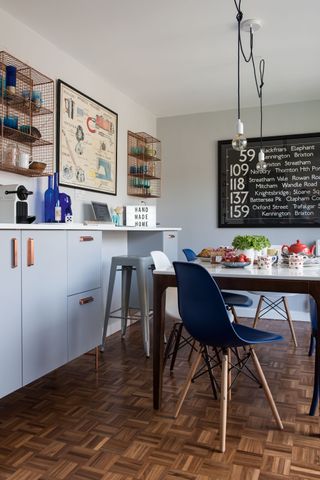 modern dining area with blue chairs, copper shelves, and art prints