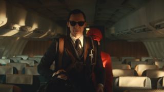 Tom Hiddleston gets ready to leave a plane while sharply dressed in Loki Season 1.
