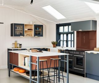 A white and dark blue kitchen with a portable kitchen island with two counter stools