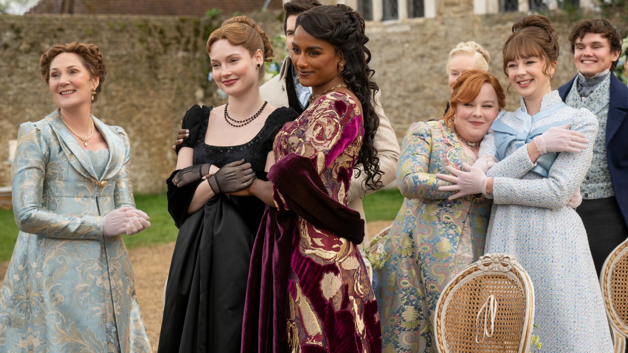 (L to R) Ruth Gemmell as Violet. Hannah Dodd as Francesca and Simone Ashley as Kate holding each other. Nicola Coughlan as Penelope hugging Claudia Jessie as Eloise. And Will Tilston as Gregory.