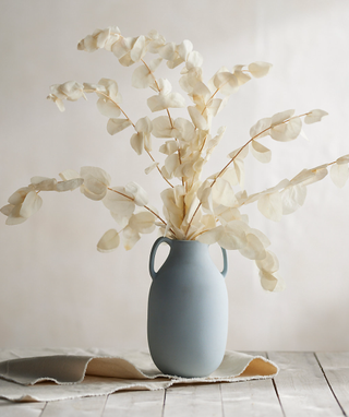 dried white eucalyptus stems in a pale blue vase